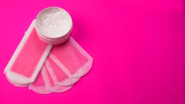 Renkli havluya bir kavanoz krem sürerek balmumu şeritlerin kapatılması, kadın tüyü temizleme konsepti