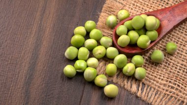 Ahşap masa arkasında yeşil bezelye yığını 