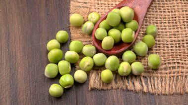 Ahşap masa arkasında yeşil bezelye yığını 