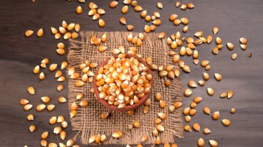 Tahta arka plandaki kilden kasede patlamamış patlamış mısır.