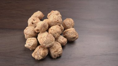 Ahşap zemin üzerinde çiğ soya parçaları yığını. Sağlıklı, besleyici soya eti, masada parçalar. Vejetaryen gıda konsepti.