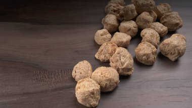 Ahşap zemin üzerinde çiğ soya parçaları yığını. Sağlıklı, besleyici soya eti, masada parçalar. Vejetaryen gıda konsepti.