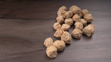 Ahşap zemin üzerinde çiğ soya parçaları yığını. Sağlıklı, besleyici soya eti, masada parçalar. Vejetaryen gıda konsepti.