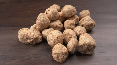 Ahşap zemin üzerinde çiğ soya parçaları yığını. Sağlıklı, besleyici soya eti, masada parçalar. Vejetaryen gıda konsepti.