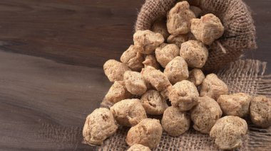 Ahşap zemin üzerinde çiğ soya parçaları yığını. Sağlıklı, besleyici soya eti, masada parçalar. Vejetaryen gıda konsepti.