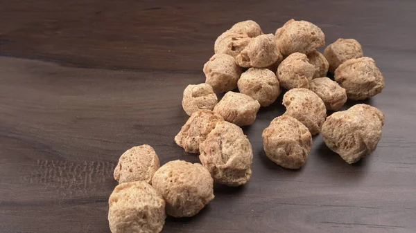 Ahşap zemin üzerinde çiğ soya parçaları yığını. Sağlıklı, besleyici soya eti, masada parçalar. Vejetaryen gıda konsepti.