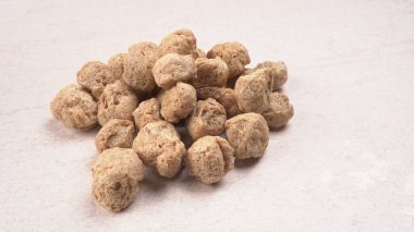 Hafif ahşap zemin üzerinde çiğ soya parçaları yığını. Sağlıklı, besleyici soya eti, masada parçalar. Vejetaryen gıda konsepti.