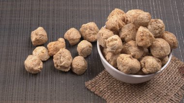 Ahşap zemin üzerinde çiğ soya parçaları yığını. Sağlıklı, besleyici soya eti, masada parçalar. Vejetaryen gıda konsepti.