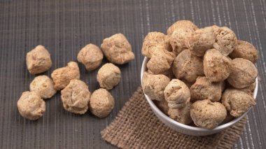 Ahşap zemin üzerinde çiğ soya parçaları yığını. Sağlıklı, besleyici soya eti, masada parçalar. Vejetaryen gıda konsepti.