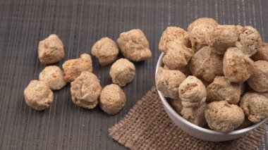 Ahşap zemin üzerinde çiğ soya parçaları yığını. Sağlıklı, besleyici soya eti, masada parçalar. Vejetaryen gıda konsepti.