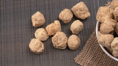 Ahşap zemin üzerinde çiğ soya parçaları yığını. Sağlıklı, besleyici soya eti, masada parçalar. Vejetaryen gıda konsepti.