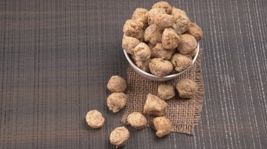 Ahşap zemin üzerinde çiğ soya parçaları yığını. Sağlıklı, besleyici soya eti, masada parçalar. Vejetaryen gıda konsepti.