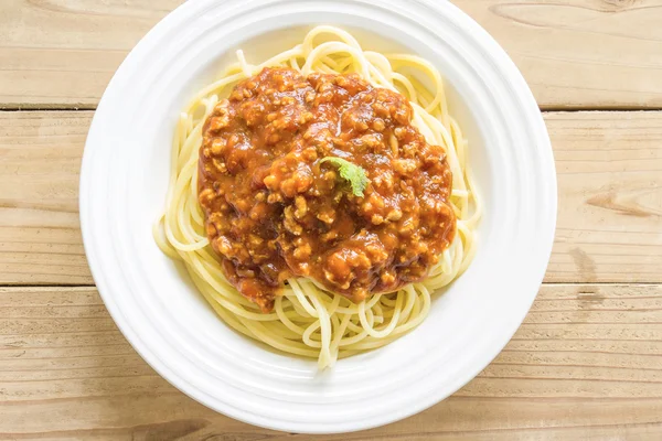 Espaguete e molho vermelho em uma chapa branca em uma mesa de madeira . — Fotografia de Stock