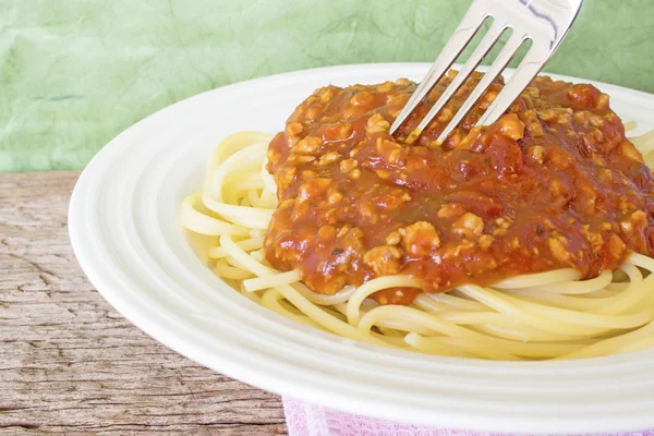 O espaguete em uma chapa branca com um garfo em um colo . — Fotografia de Stock