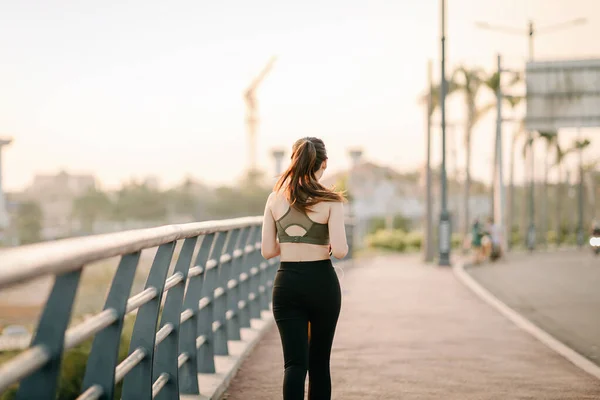 Spor giyimli güzel Asyalı kadınlar gün batımında parkta egzersiz yaparken müzik dinliyorlar. Sağlıklı kadın kavramı.