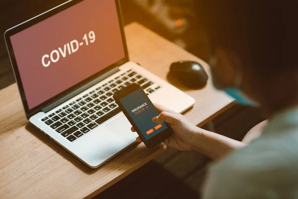 Kadınlar, Corona virüsü (Covid-19) sigortasını kaydetmek veya kaydetmek için ellerinde akıllı telefon tutuyorlar. Haberleri kontrol ettikten sonra internette virüs yayılıyor. Sigorta konsepti