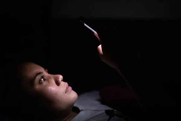 Gece geç saatlerde akıllı telefon kullanan Asyalı kadınların yakın çekimleri, uyuyamıyorum. Uyku bozukluğu kavramı.