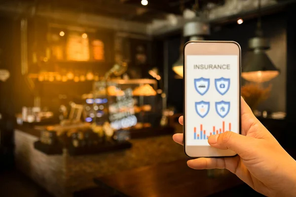 İnternette sigorta aramak için el ele tutuşan akıllı telefon. Sigorta konsepti
