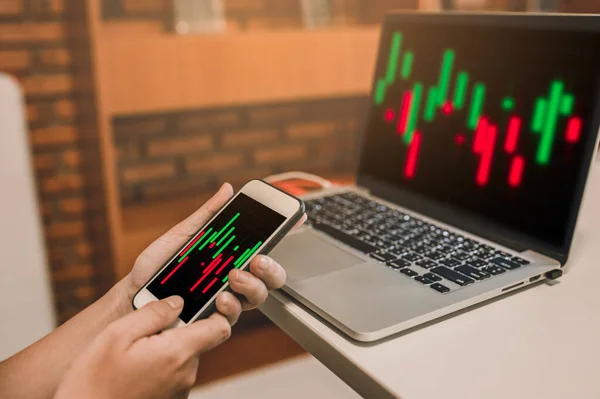 Finansal hisse senedi verileri ve parmaklarıyla akıllı telefondan alım satımı kontrol ediliyor.