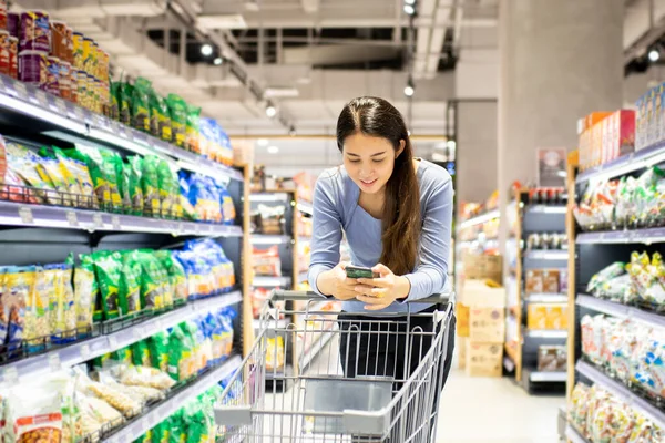 Güzel genç Asyalı kadın süpermarkette alışveriş arabası itiyor. Alışveriş süpermarketi konsepti.
