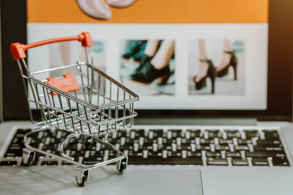 Shopping cart with computer laptop on a table. Concept for shopping online or e-commerce from internet for Coronavirus COVID-19 disease protection.