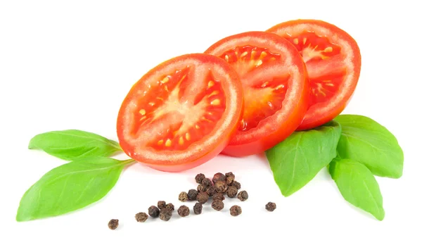Dilimlenmiş domates fesleğen yaprakları ve siyah üzerinde beyaz izole biber ile