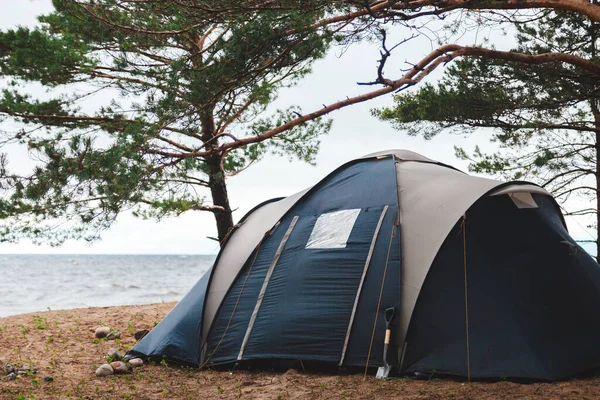 Blue camping tent on the lake shore, savage recreation and travel