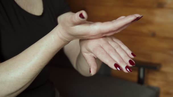 Женщина среднего возраста наносит ежедневный крем на руки дома, пожилая концепция кожи — стоковое видео