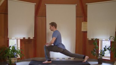 Yakışıklı beyaz erkek sırt ve bacak kasları için ev içi egzersiz yapıyor.