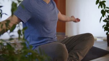 Spor kıyafetleri içinde loto pozisyonunda oturmuş meditasyona hazırlanan atletik bir erkeğin orta kısmı.