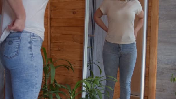 Section du milieu de la femme adulte en vêtements décontractés vérifier son corps moyen dans le miroir — Video