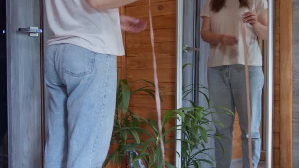 Środkowa część smukłej 30-tki starsza kobieta mierzy talię taśmą i patrzy na własne odbicie w lustrze w domu — Wideo stockowe