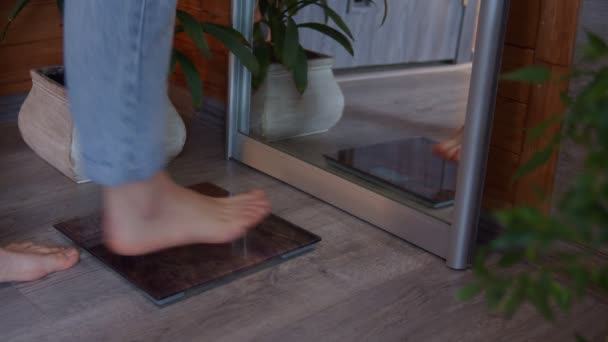 Close-up van vrouwelijke voeten op schaal, onherkenbare vrouw staan op gewicht-schalen afslanken thuis — Stockvideo
