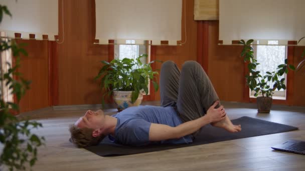 Wellness, jongeman doet yoga in de kamer thuis, man voert de brug pose in de buurt van ramen — Stockvideo