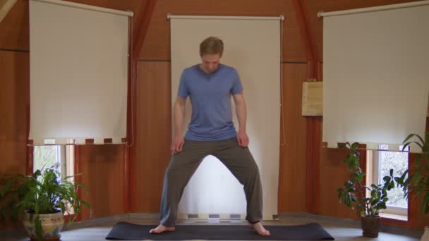 Hubený mladý muž stojící bosý na výcvikové podložce dělá protahování cvičení doma — Stock video