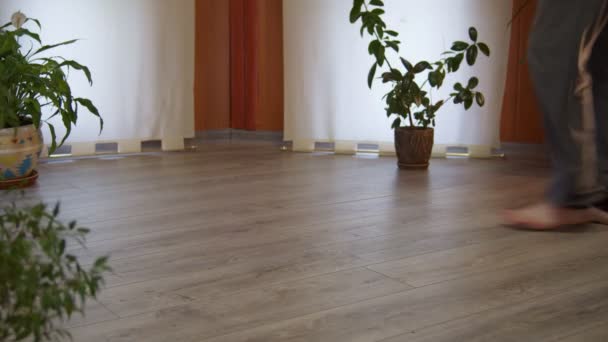 Vista frontal del hombre descalzo desplegando su esterilla de yoga negro en el dormitorio en casa — Vídeo de stock