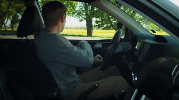 Mannen som sitter i en bil och sätter på sig säkerhetsbältet och börjar köra — Stockvideo