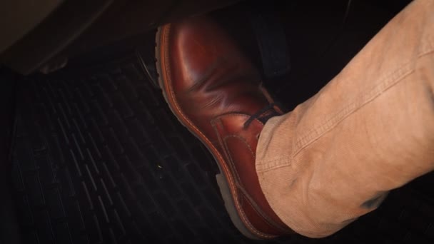 Mannen i bruna skor trycker på bromspedalen i en modern bil — Stockvideo