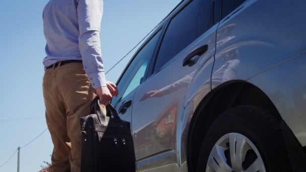 Jeune homme en vêtements décontractés avec sac en cuir monter dans une voiture — Video