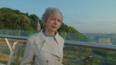 Yaşlı sakallı adam gri saçlı kadına yaklaşıyor ve çiçekleri sunuyor.