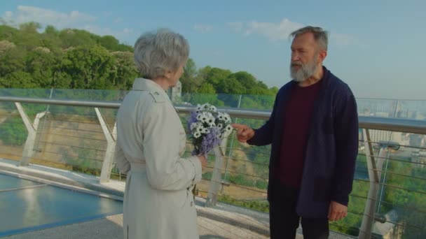 Äldre skäggiga man och kvinna med blommor som grälar utomhus — Stockvideo