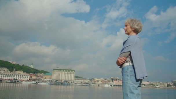 Пожилой красивый мужчина заботится о своем очаровательном мечтательном партнере на реке — стоковое видео