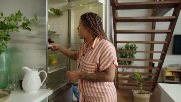 Asiatisk kvinna hindrar svart kvinna från att äta ohälsosam mat inomhus — Stockvideo