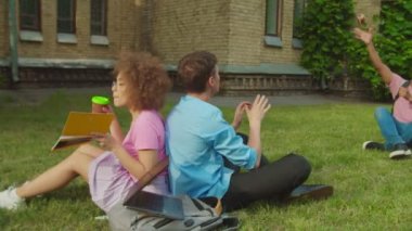 Carefree male students with ball vs student girls with coffee outdoors
