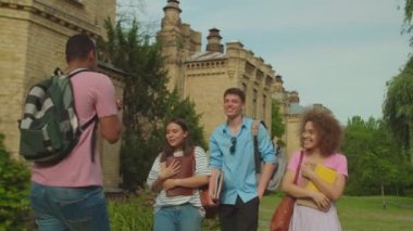 Young man going backwards, telling stories to diverse friends outdoors