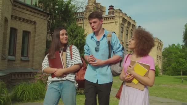 One cheerful student catching up young college friends outdoors — Vídeo de Stock