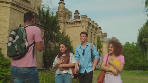 Young man going backwards, telling stories to diverse friends outdoors — Vídeo de Stock