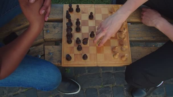 Twee scholieren spelen schaakspel op de bank buiten bij zonsondergang — Stockvideo