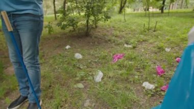 Çok ırklı bir grup öğrenci dışarıda plastik çöp topluyor.