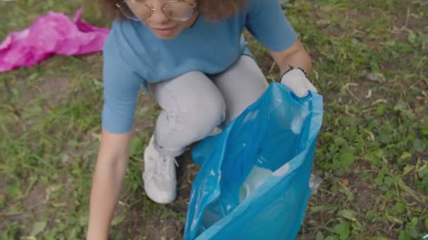 Close-up de menina consciente ambiental pegando plástico em saco de lixo — Vídeo de Stock